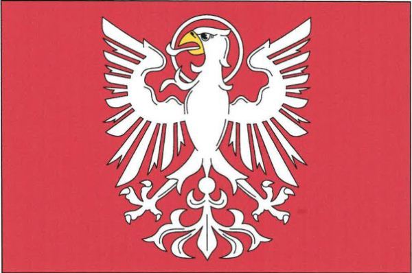 Červený list s bílou orlicí s kruhovou svatozáří a žlutým zobákem. Poměr šířky k délce je 2:3.